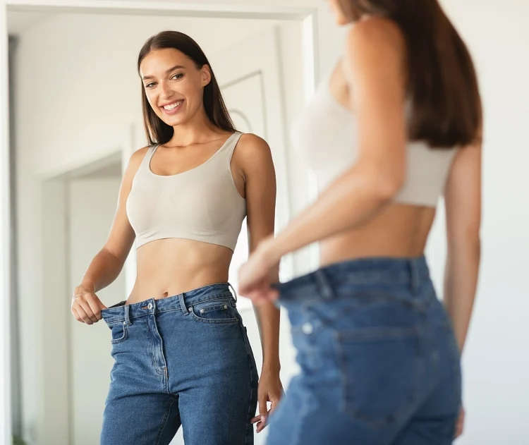 Woman looking in the mirror after weight loss